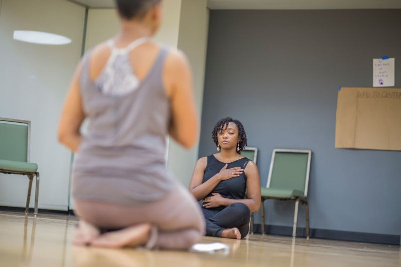 Two people meditating on the floor at the AMC