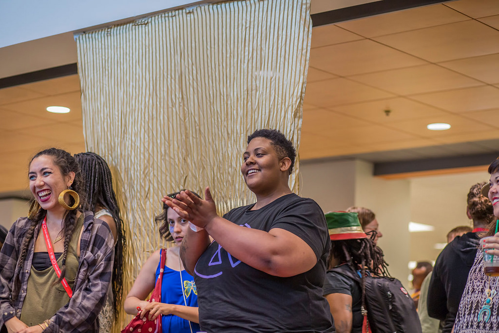 Morgan Willis smiling at the AMC with open hands, with attendees