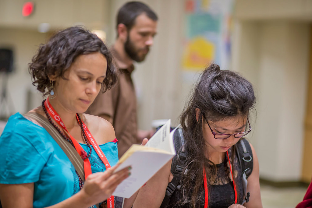 Three attendees of the AMC at a table looking through the program