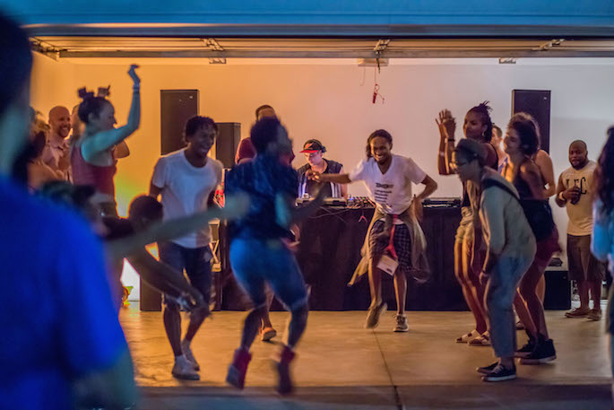 A group of people dancing in front of a DJ booth