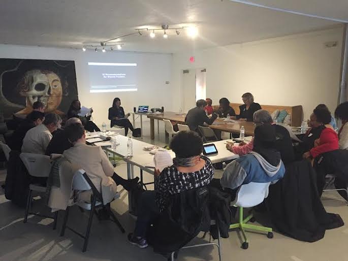 A room with tables in a U shape with funders and community organizers reading together