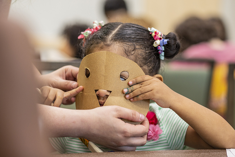 Child at the AMC with a handmade mask they made on their face