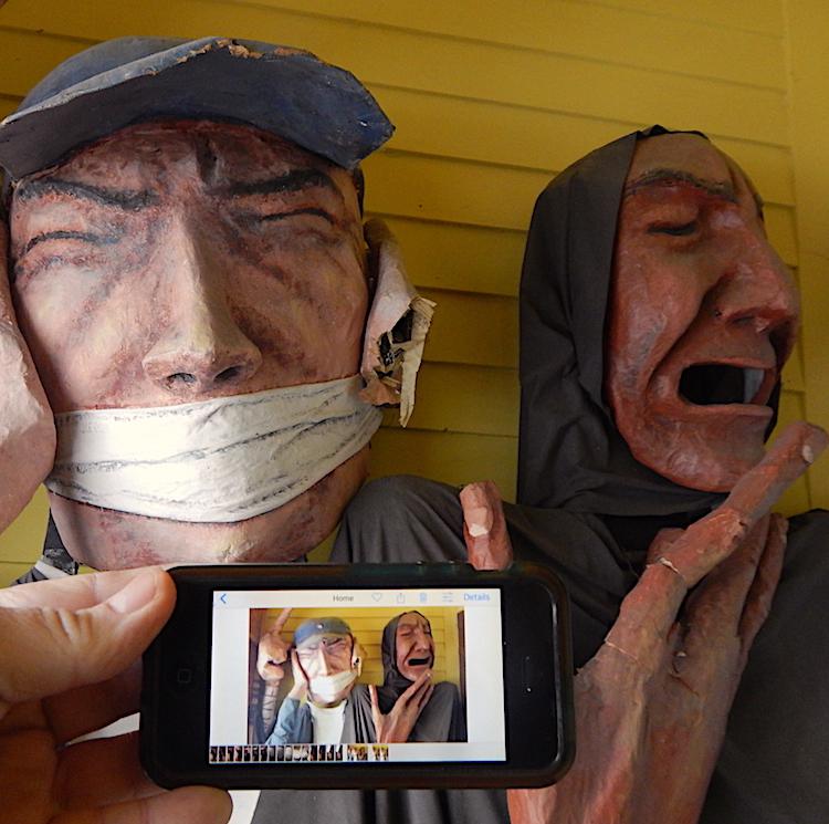 An iPhone picture gallery showing a picture of two sculptures that are also in the background, one with their mouth bound and the other with agnst on their face