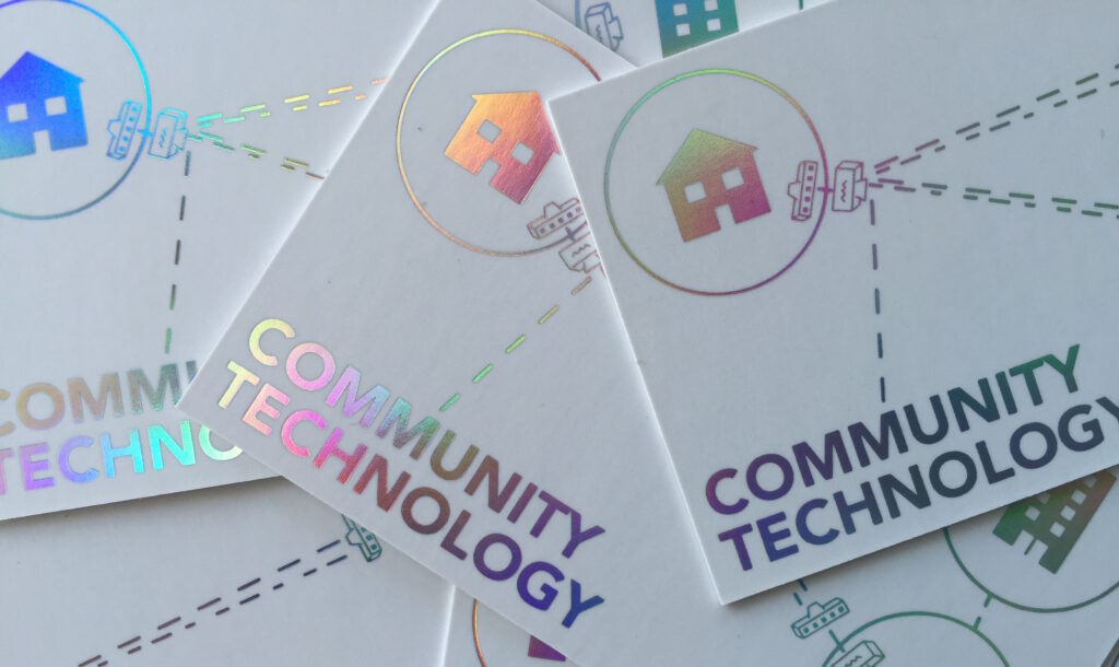 Close up of DCTP business cards in with the words "Community Technology" with dotted lines connecting icons of houses and buildings all with iridescent link