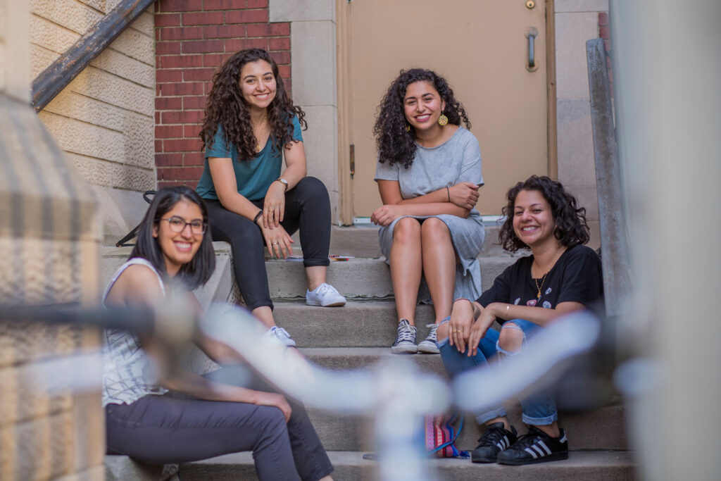 Four women AMC attendees sitting together on stairs