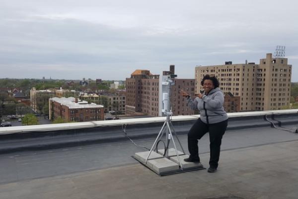 EII Digital Steward posing with a wireless mesh network satellite on a roof top