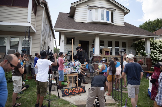 A person tells a story from their porch with people gathered