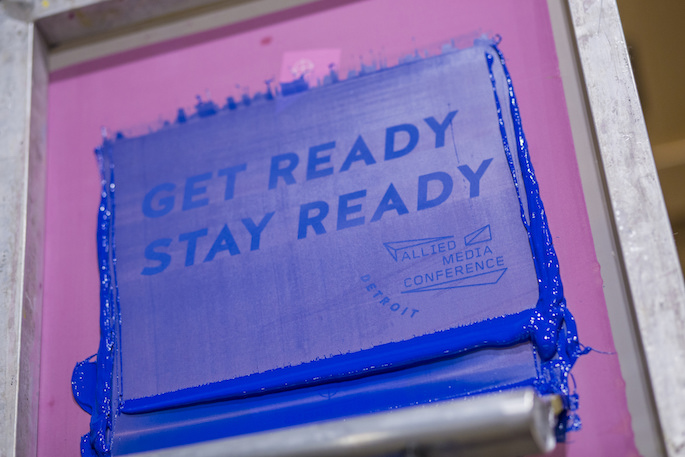 Screen with ink and roller screen printing the words "Get Ready Stay Ready"