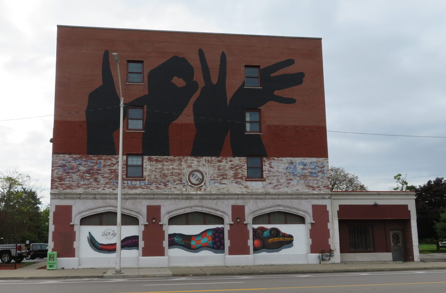 Photo of the LOVE Building at 4731 Grand River, Detroit. A four-story brick building painted with the word "LOVE" spelled out using hands.