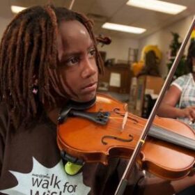 Young Black child playing a violin in a classroom