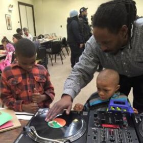 An adult and two children working with dj equipment