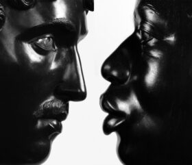 Close up of two sculptued black faces nearly touching each other